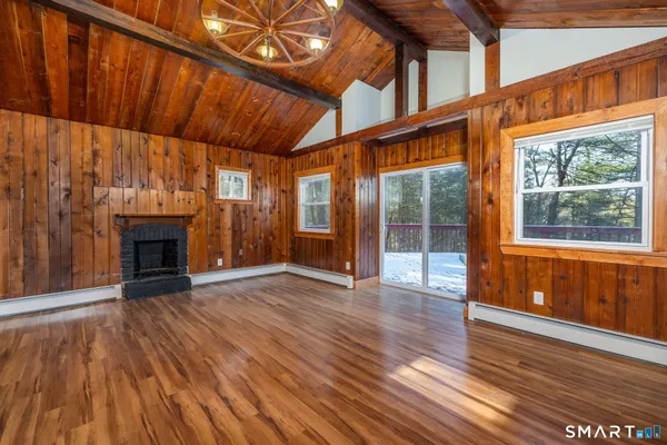 a view of an empty room with wooden floor fireplace and a window