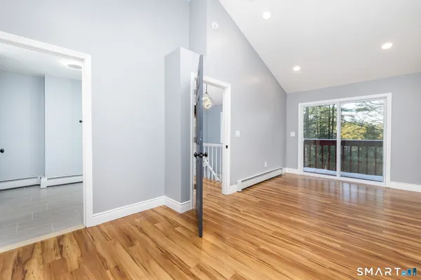 a view of empty room with wooden floor and fan
