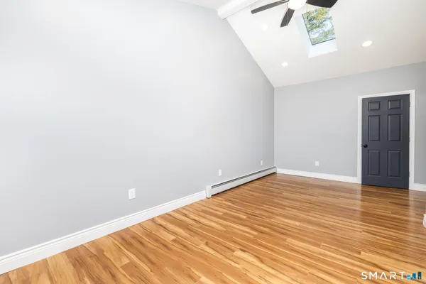 a view of an empty room with wooden floor and a window