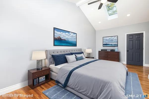 a spacious bedroom with a bed and a lamp on table