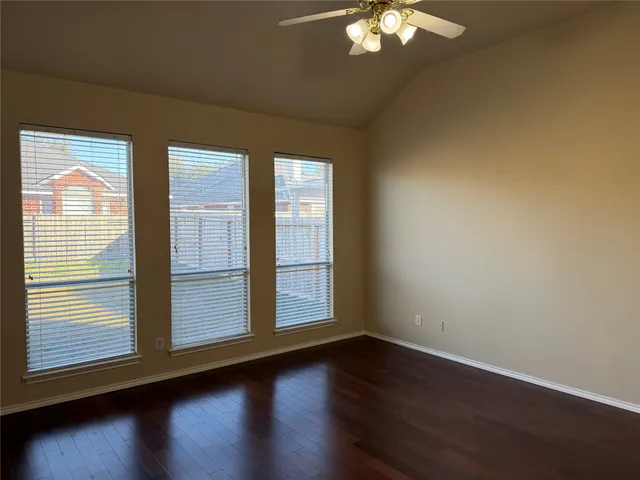an empty room with wooden floor closet and windows