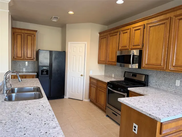 a kitchen with granite countertop a stove a sink and a microwave