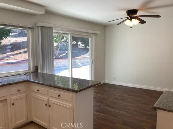 a kitchen with granite countertop a stove and white cabinets with wooden floor