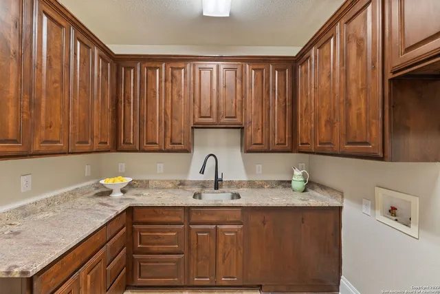 a kitchen with granite countertop stainless steel appliances a sink dishwasher and cabinets with wooden floor
