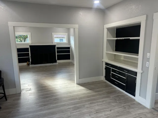 a view of an empty room with kitchen and window