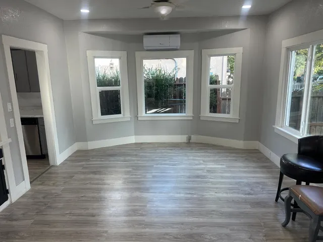 a view of an empty room with a window and wooden floor