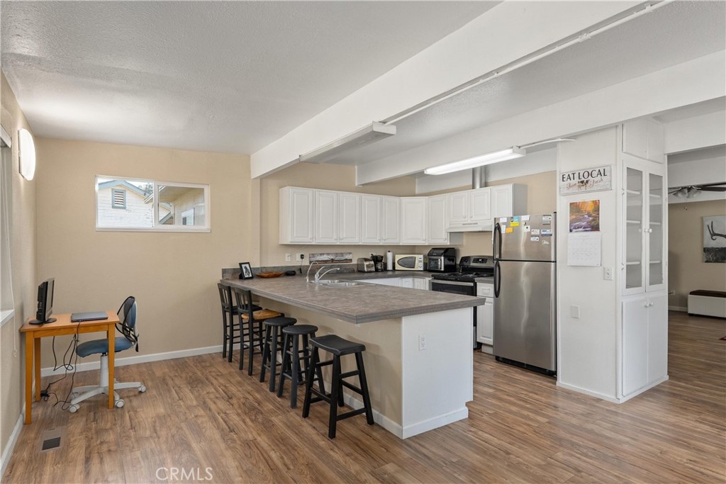 5574 California Street Chico, CA 95973 - Photo 10 of 30 a kitchen with kitchen island a stove a refrigerator and a dining table with wooden floors