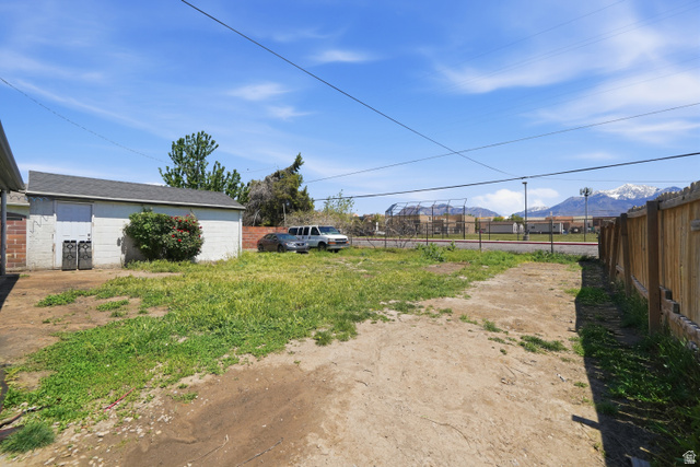 7879 Oak Street Midvale, UT 84047 - Photo 30 of 32 Spacious rear yard featuring a detached garage, partial wood fencing, and mountain scenery