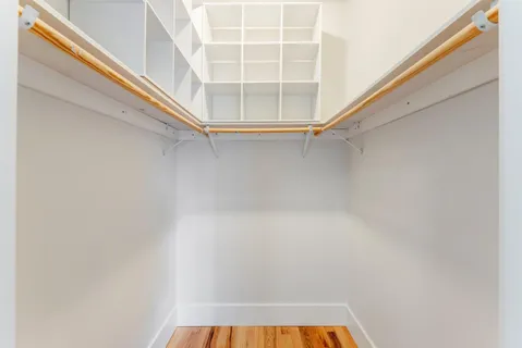 a view of a hallway with wooden floor and a bathroom