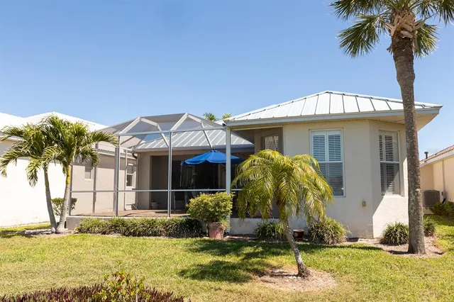 a view of a white house with a small yard and large trees