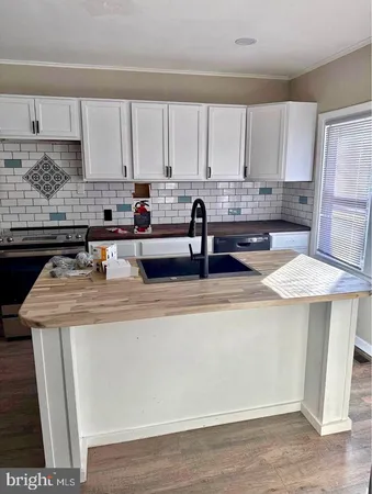 a kitchen with stainless steel appliances granite countertop a sink a stove and white cabinets