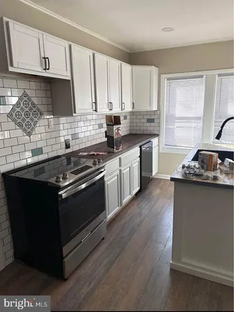 a kitchen with granite countertop wooden cabinets stove top oven and sink