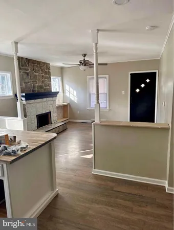 a living room with stainless steel appliances kitchen island hardwood floor and a fireplace