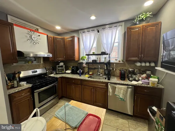 a kitchen with stainless steel appliances granite countertop a stove top oven a sink dishwasher and cabinets with wooden floor