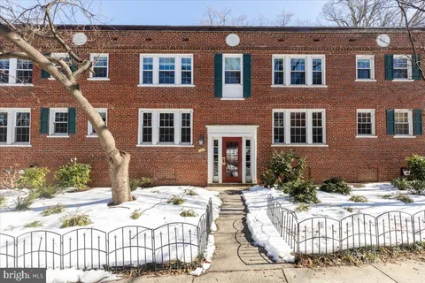 a view of a brick house with plants and wooden fence