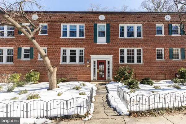 a view of a brick house with plants and wooden fence