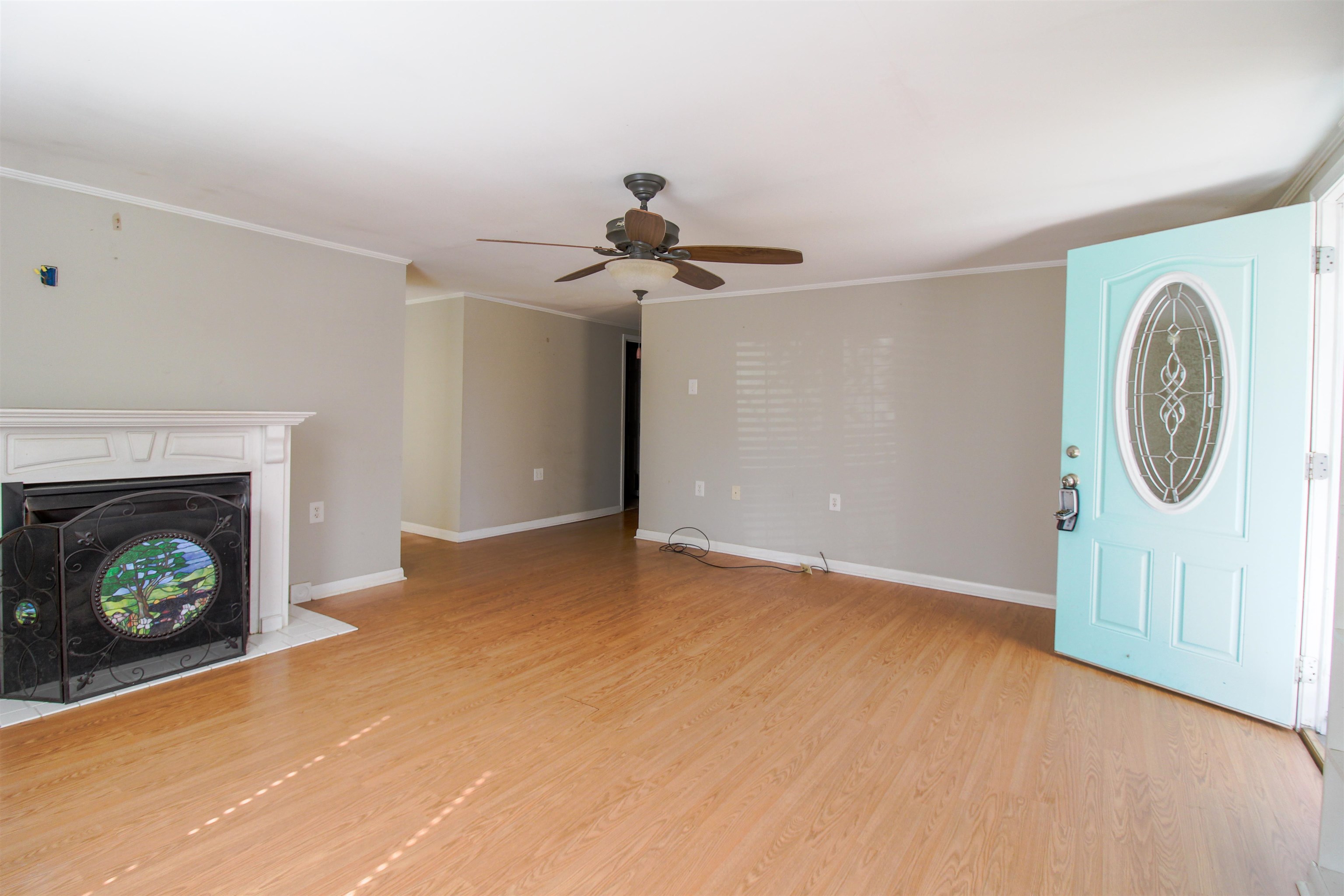 143 Marys Chapel Road Ripley, TN 38063 - Photo 3 of 23 Living room featuring light wood-style flooring, ornamental molding, ceiling fan, built ins and fireplace.