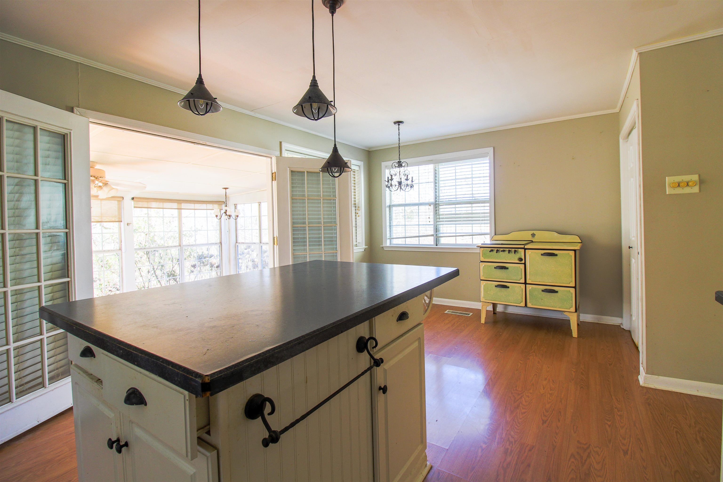 143 Marys Chapel Road Ripley, TN 38063 - Photo 4 of 23 Kitchen featuring dark countertops, a center island, dark wood-style floors, crown molding, and a chandelier