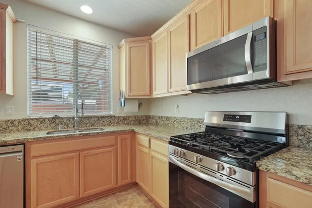 a kitchen with stainless steel appliances granite countertop white cabinets and window