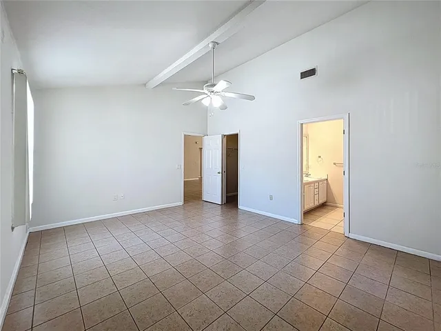 an empty room with chandelier fan and windows