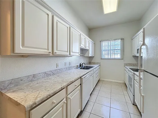 a kitchen with granite countertop white cabinets and stainless steel appliances
