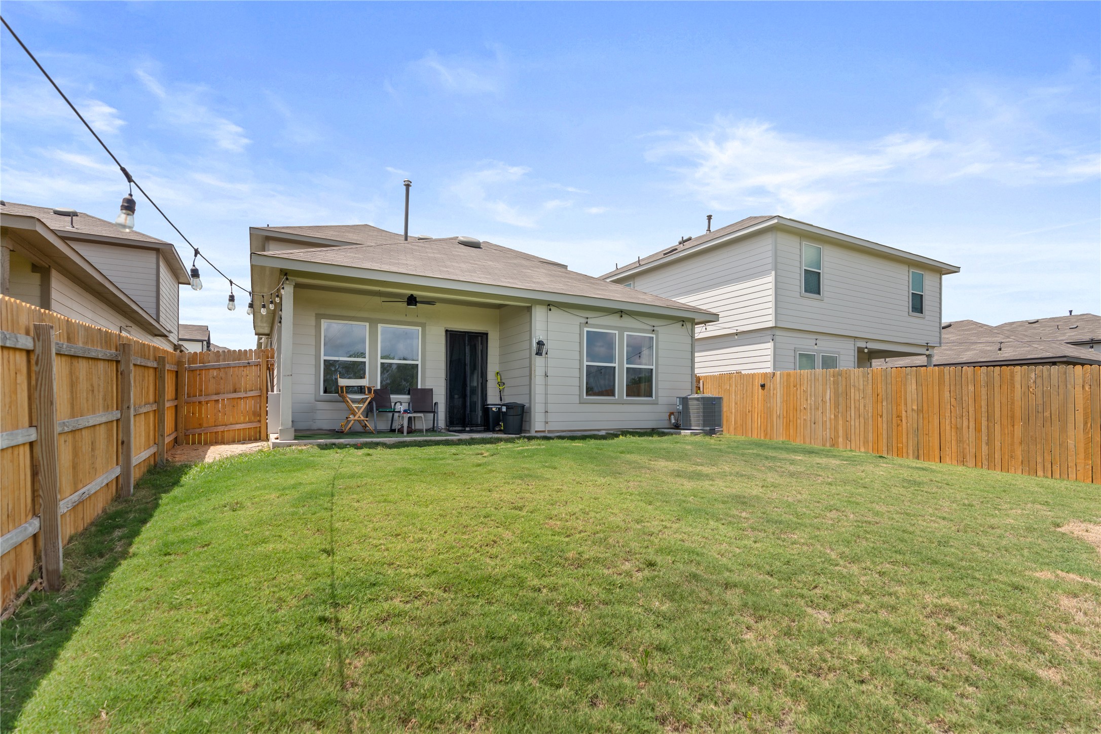143 Santa Rosa Lane Buda, TX 78610 - Photo 26 of 28 Rear view of house with a ceiling fan, a fenced backyard, and a patio