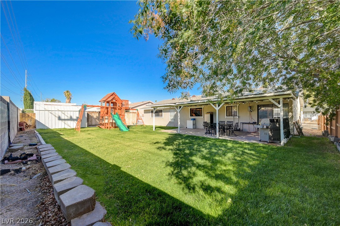 1331 Pinto Road Boulder City, NV 89005 - Photo 41 of 46 Generous green lawn with covered patio, ideal for outdoor gatherings and recreation.
