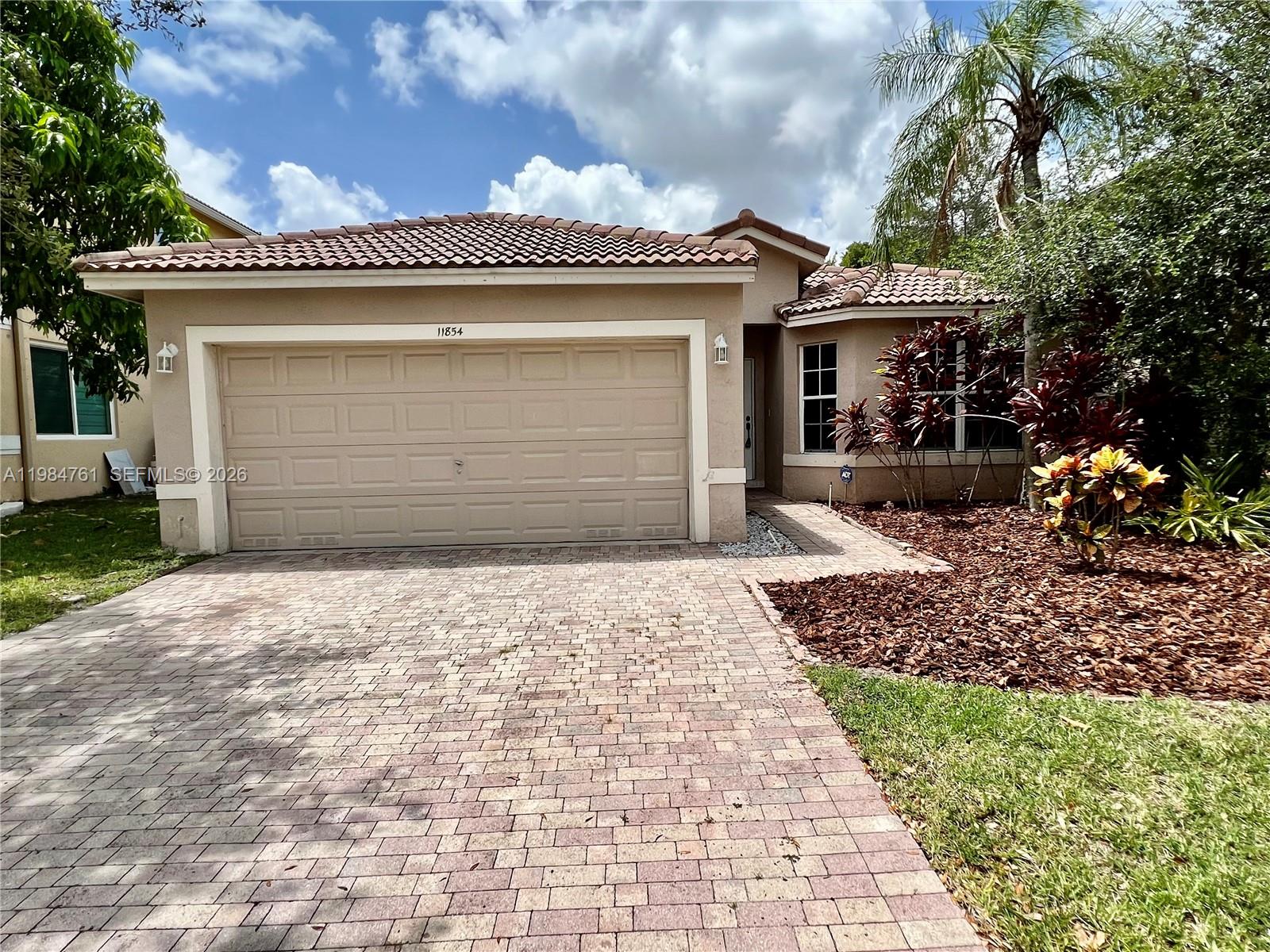 11854 Southwest 8th Street Pembroke Pines, FL 33025 - Photo 2 of 11 a front view of a house with a garden