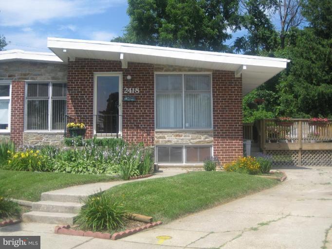a view of a house with brick walls and a yard with plants and a lawn chairs with plants