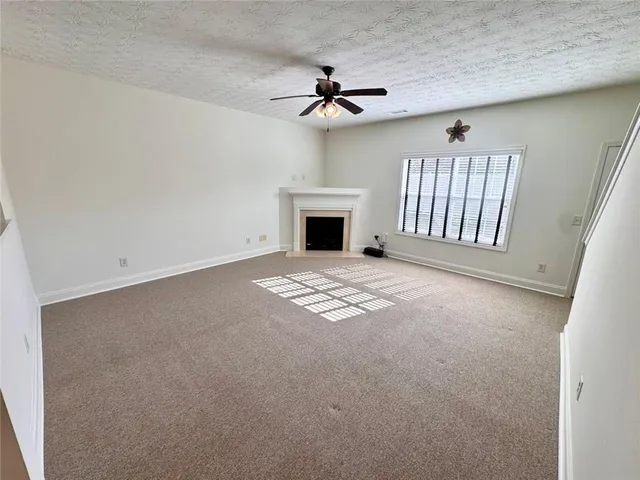 a view of an empty room with a fireplace and a window
