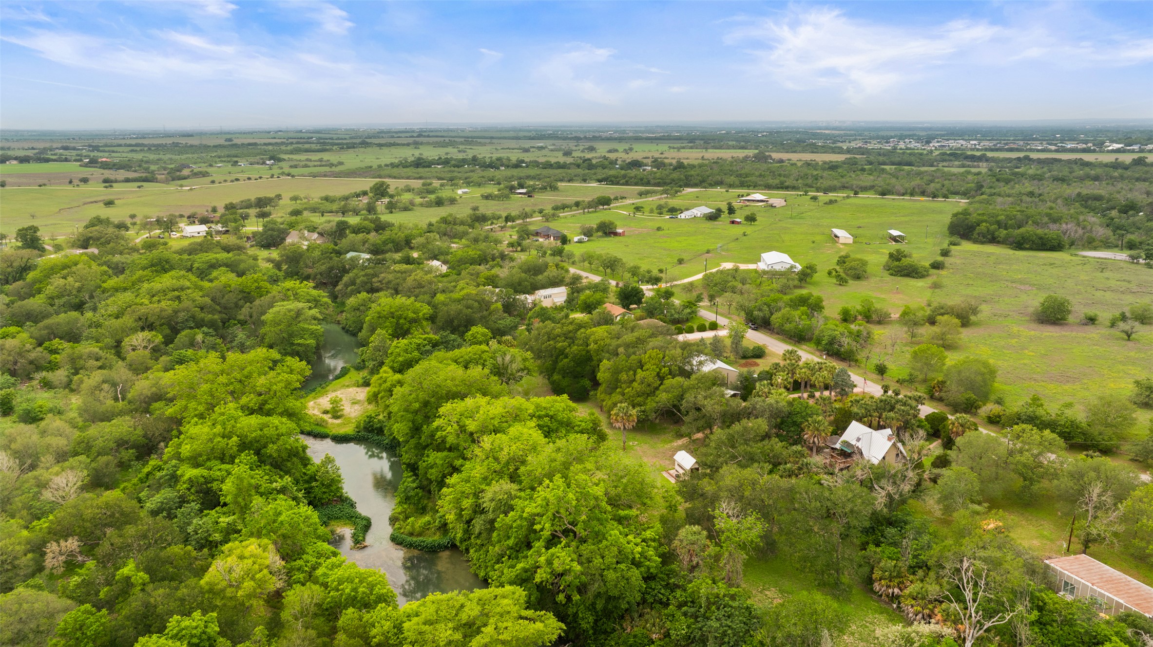 664 Martindale Falls Road Martindale, TX 78655 - Photo 7 of 21 Expansive landscape featuring abundant mature trees, a natural watercourse, and multiple residential structures