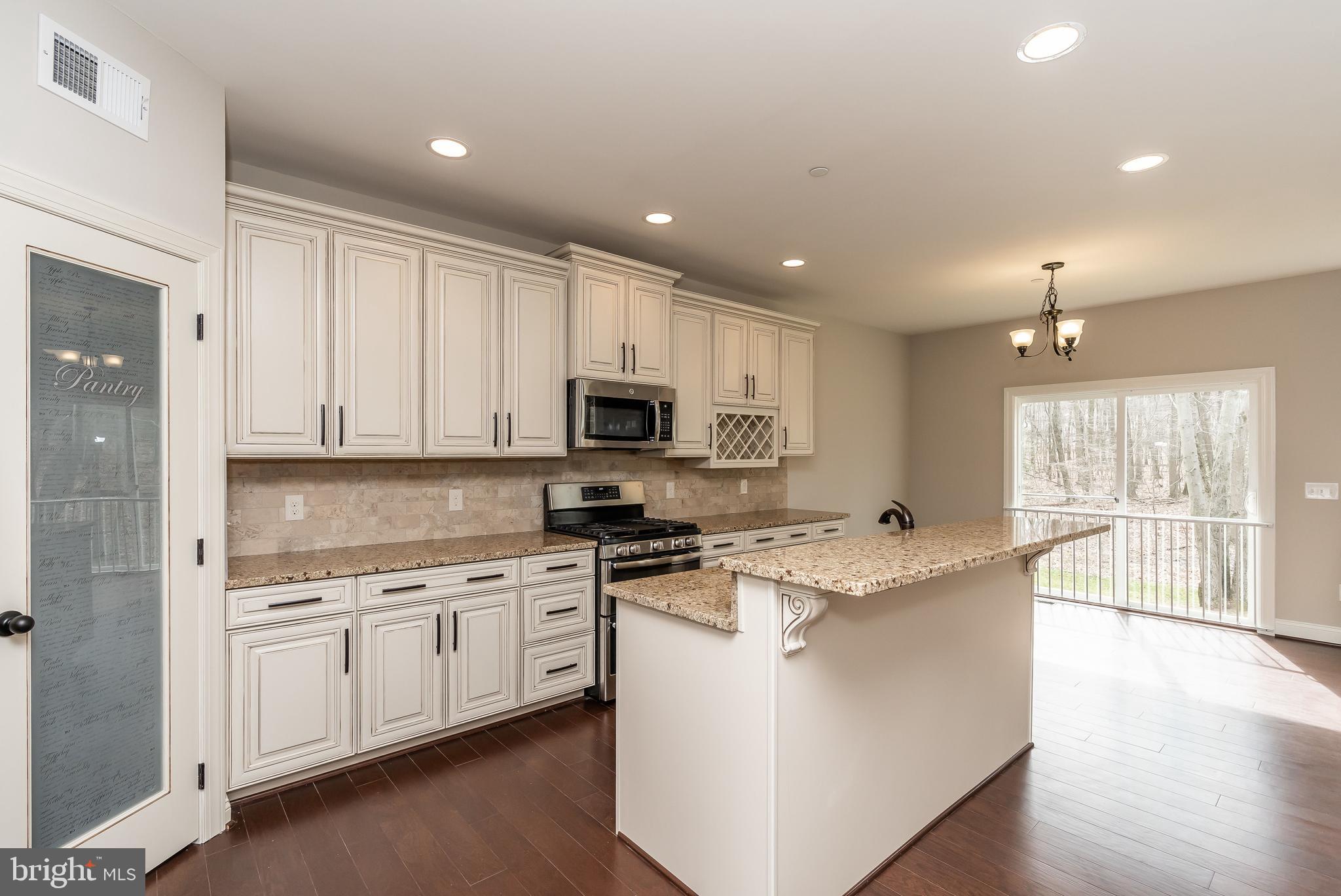 470 Queenstown Road Severn, MD 21144 - Photo 21 of 56 a kitchen with stainless steel appliances granite countertop a stove top oven a sink a refrigerator and white cabinets with wooden floor