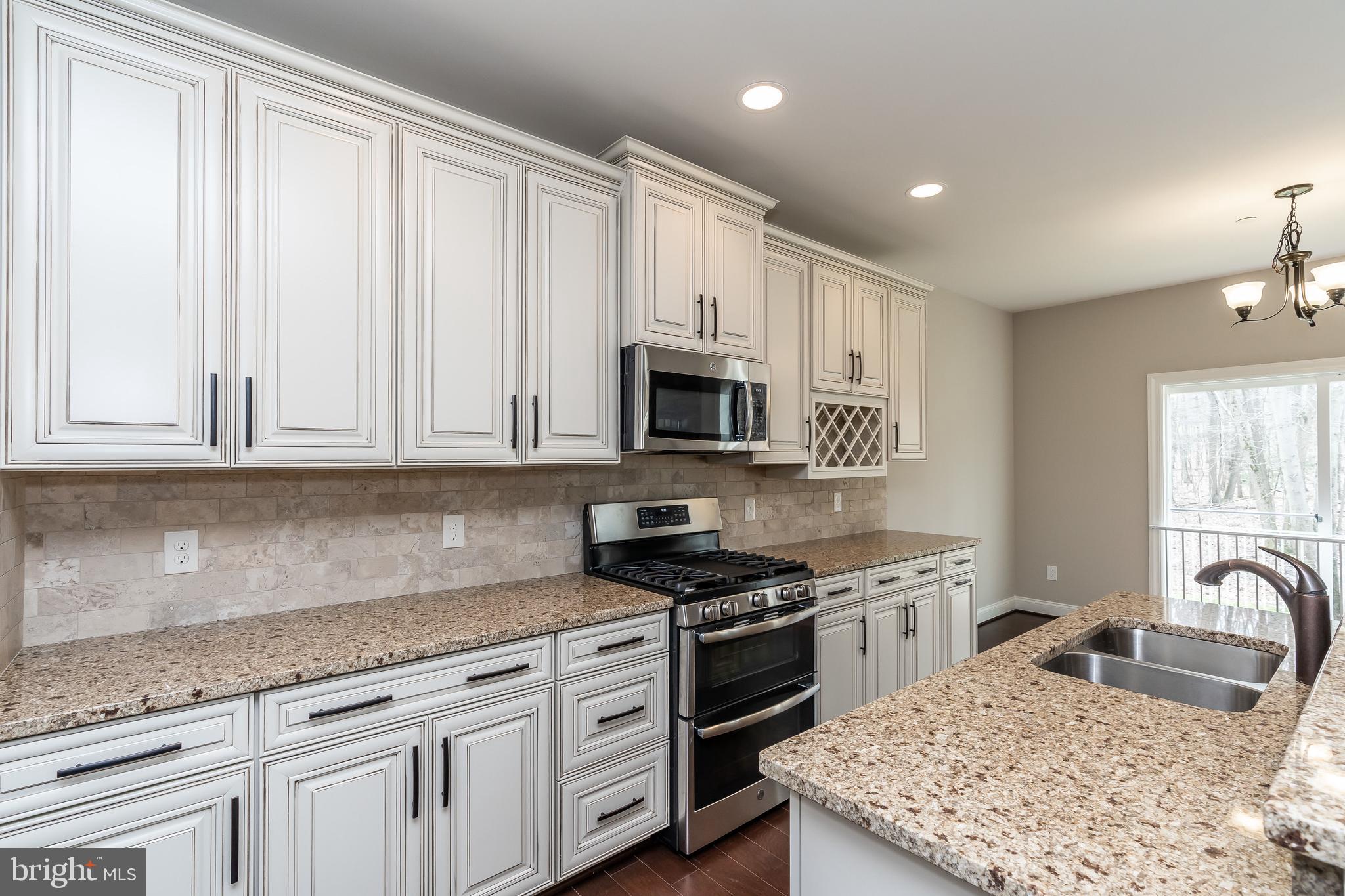 470 Queenstown Road Severn, MD 21144 - Photo 22 of 56 a kitchen with granite countertop a sink stainless steel appliances and white cabinets