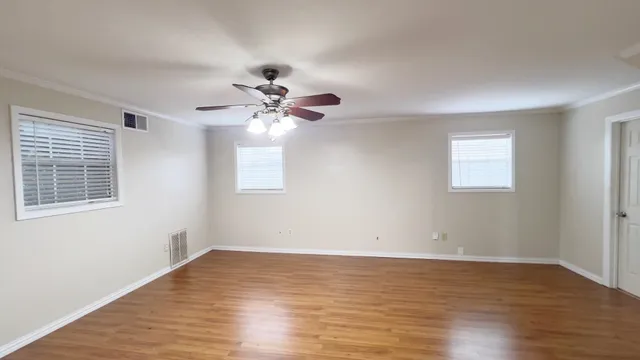 a view of an empty room with wooden floor and a window