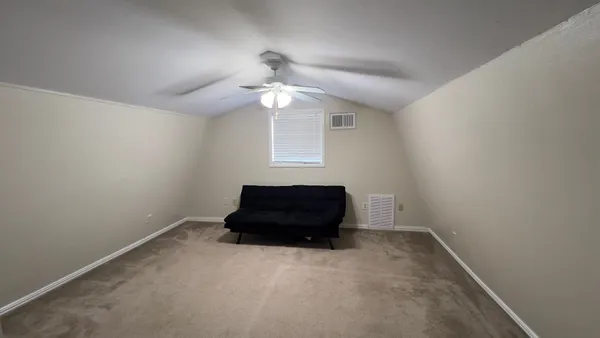 an empty room with a ceiling fan and window