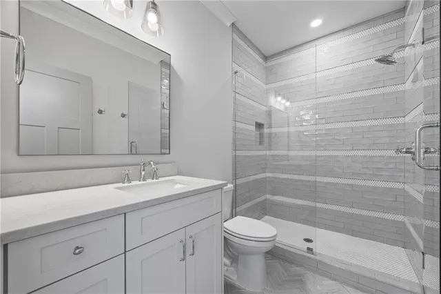 a bathroom with a toilet a sink a glass door shower and a mirror