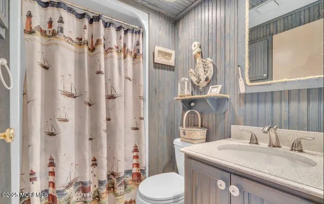 a bathroom with a granite countertop sink a toilet and a shower curtain