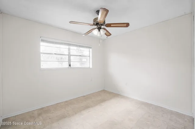 an empty room with a window and a fan