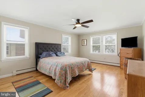 a bedroom with a bed television on desk and a window
