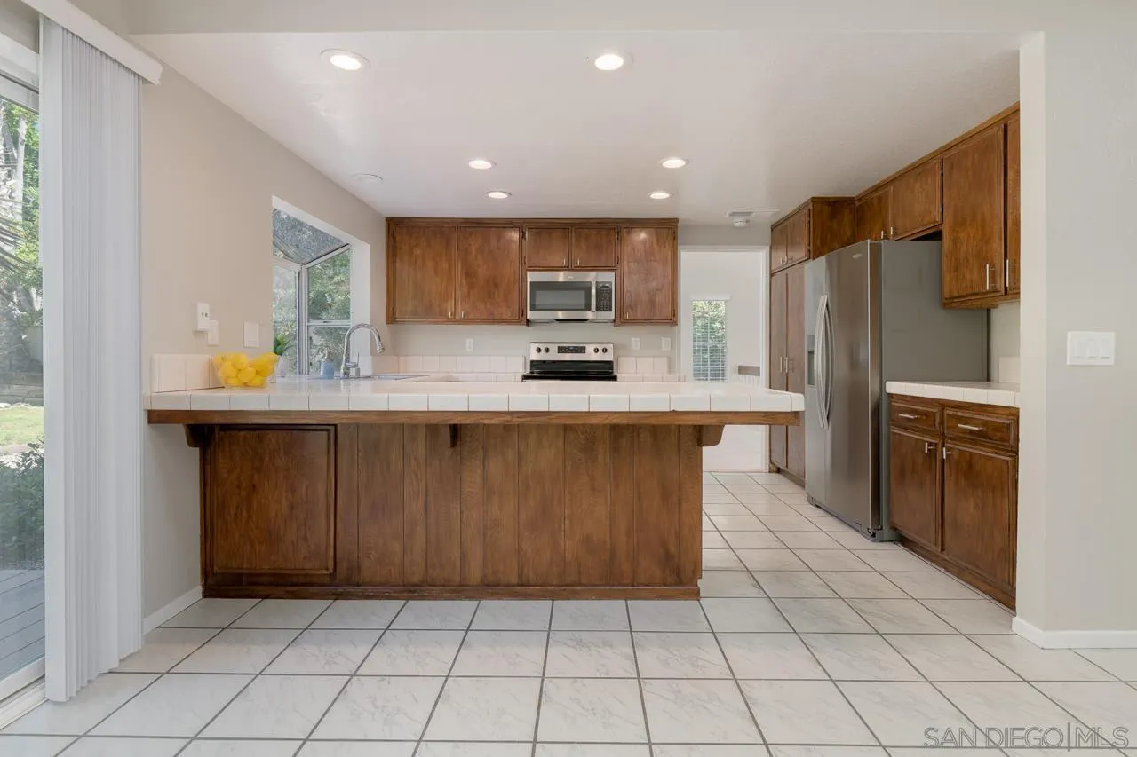 1908 Hummock Lane Encinitas, CA 92024 - Photo 16 of 29 a kitchen with kitchen island granite countertop a stove a sink a refrigerator and a refrigerator