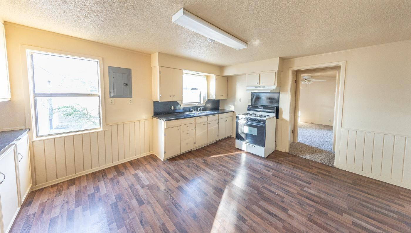 3007 Emory Street Lubbock, TX 79415 - Photo 5 of 17 a kitchen with stainless steel appliances granite countertop a stove top oven a sink with wooden floors and cabinets