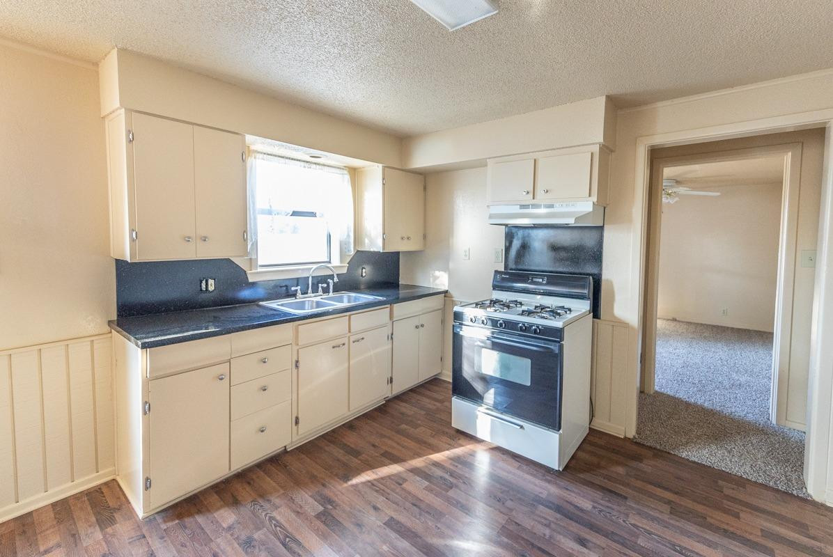 3007 Emory Street Lubbock, TX 79415 - Photo 7 of 17 a kitchen with granite countertop a stove a sink and a refrigerator