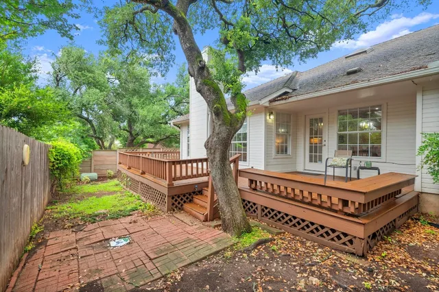 a view of a house with wooden deck and a forest