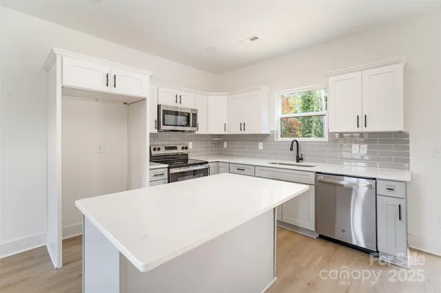 a kitchen with stainless steel appliances a sink a stove a refrigerator cabinets and a window