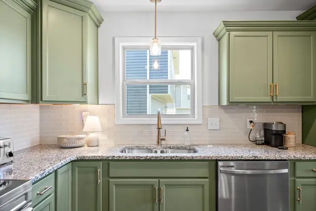 a kitchen with granite countertop a sink stainless steel appliances white cabinets and a granite counter top