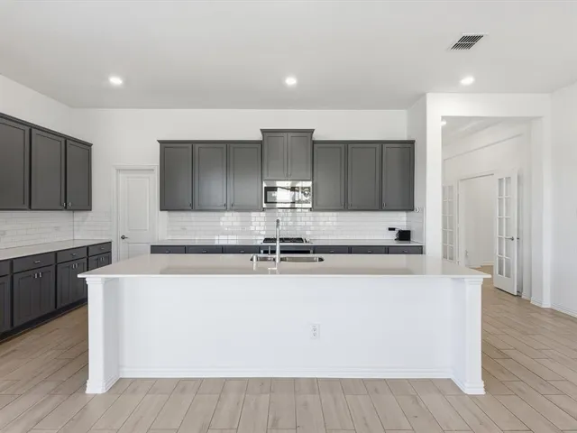 a large kitchen with stainless steel appliances granite countertop a stove a sink and a refrigerator