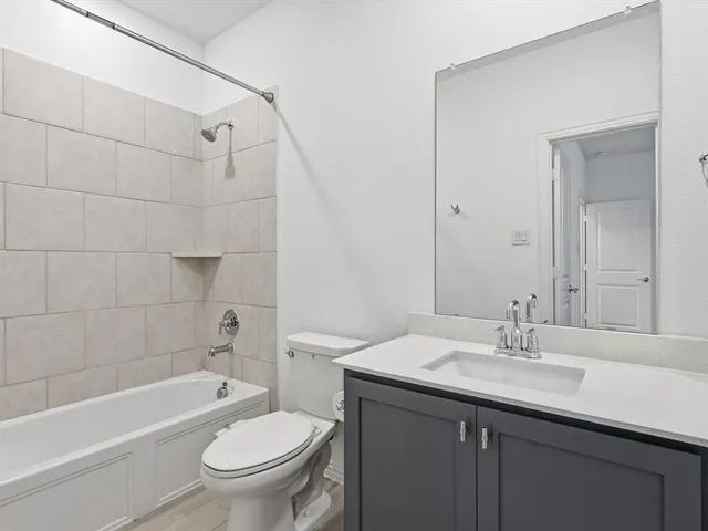 a bathroom with a toilet a sink a mirror a bathtub and shower