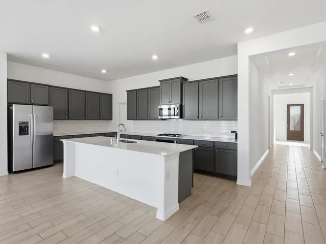 a large kitchen with stainless steel appliances granite countertop a large counter top and a stove top oven