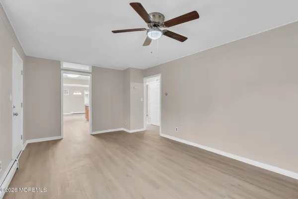 an empty room with wooden floor and ceiling fan