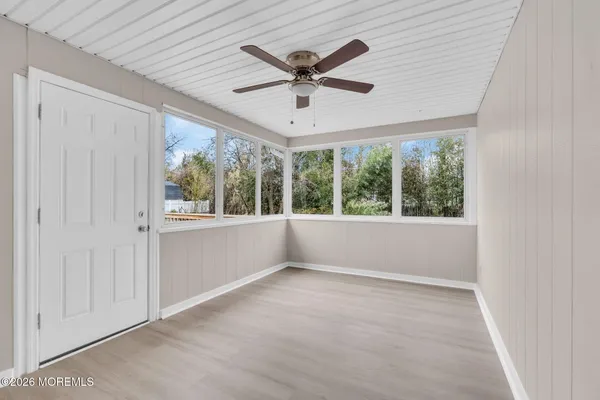 an empty room with windows and ceiling fan